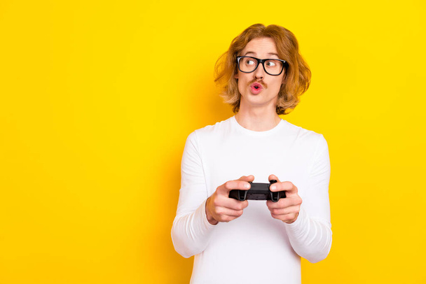 Photo of impressed funky guy wear white shirt spectacles holding playstation looking empty space isolated yellow color background - Photo, image