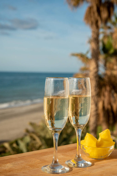 Outdoor breakfast in sunny day with Spanish cava sparkling wine and pineapple and view on blue sea and sandy beach in Marbella, Costa del Sol vacation destination, Andalusia, Spain - Φωτογραφία, εικόνα