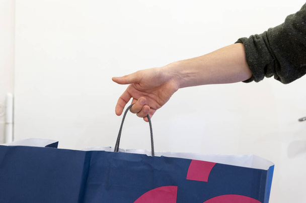 hand holding a shopping bag with a red ribbon - Φωτογραφία, εικόνα