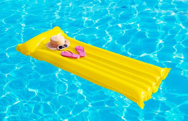 Beach summer holiday background. Inflatable air mattress, flip flops and hat on swimming pool. - Photo, Image