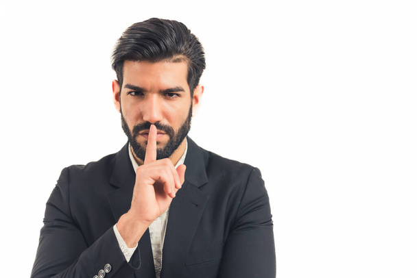 Schöner stylischer hispanischer Chef zeigt Schweigefingergeste - isoliertes Portrait auf weißem Studiohintergrund - Foto, Bild