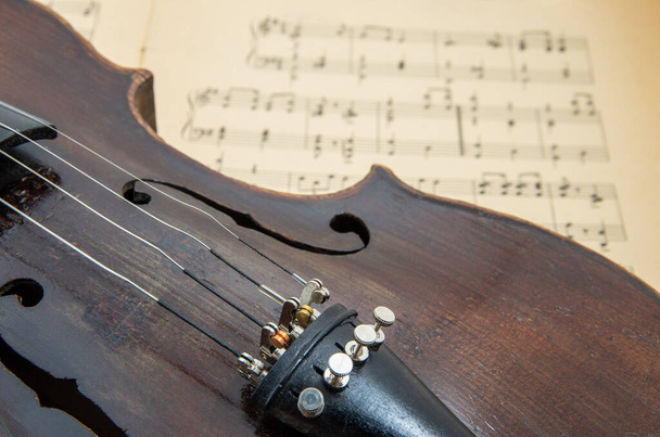 Παλιό βιολί ξαπλωμένο στο σεντόνι της μουσικής, μουσική έννοια - Φωτογραφία, εικόνα