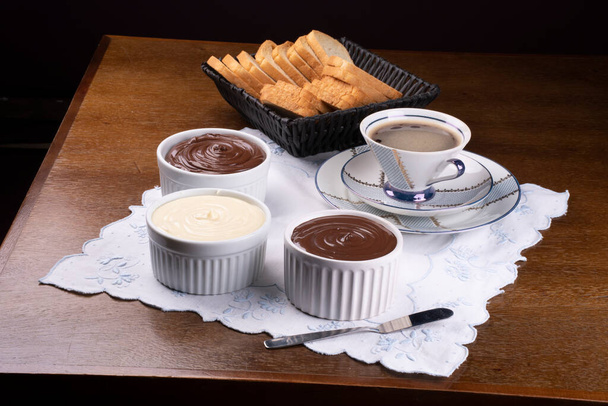 κρέμα φουντουκιού, σοκολάτας και λευκής σοκολάτας με βάφλες στο τραπεζάκι του πρωινού και θέα γωνία καλαθιού ψωμιού - Φωτογραφία, εικόνα