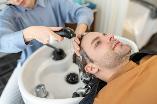 Hairdresser washing hair to the male client in a beauty salon - Photo, image