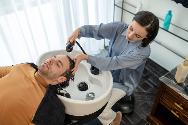 Beautician washing hair to the client and massaging his head - Valokuva, kuva