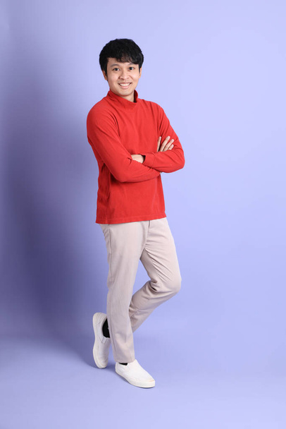 The young adult southeast Asian man with red long sleeve shirt standing on the light green background. - Fotó, kép
