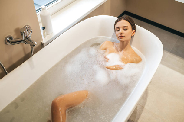 Beautiful calm woman dozing in the bath - Photo, image