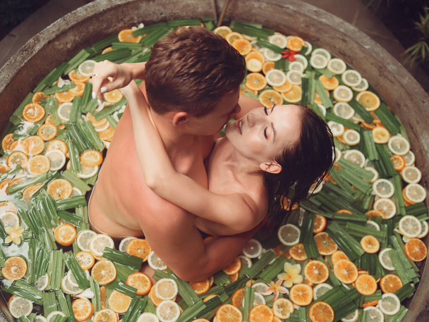 Paar liegt in rundem Bad mit Früchten - Foto, Bild