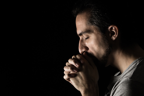 Muž skládající ruce v modlitbě k Bohu na černém pozadí. modlitba k Bohu za štěstí a lepší život. Čiň pokání ze svých hříchů. Jednota s Bohem - Fotografie, Obrázek