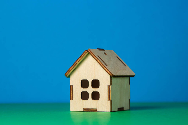 Небольшой деревянный игрушечный домик на цветном фоне. Концепция купли-продажи недвижимости. услуги по недвижимости - Фото, изображение