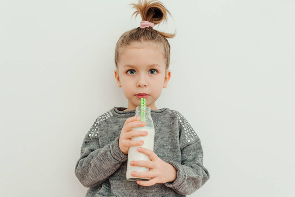 Söpö tyylikäs pieni tyttö muoti kampauksen juominen maitoa. Valkoinen tausta, studio ammuttu - Valokuva, kuva