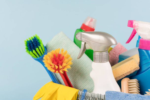 Kit de productos de limpieza sobre fondo de pared azul con espacio para copiar. Concepto de servicio de limpieza, detergentes domésticos - Foto, Imagen