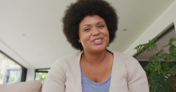 Video of happy plus size african american woman having video call. lifestyle, leisure, spending free time at home with technology. - Materiał filmowy, wideo