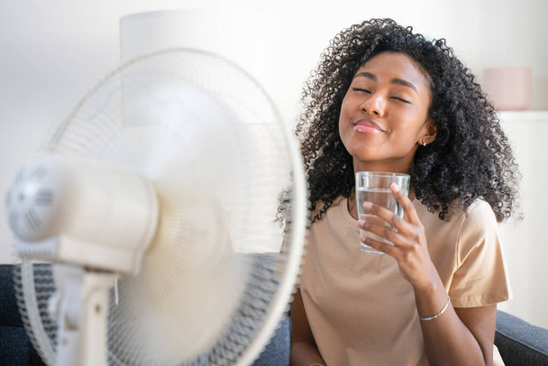 Одна чорна жінка з вентилятором почувається дуже гарячою
 - Фото, зображення
