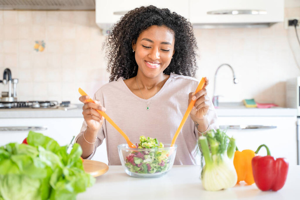 One black woman preparing vegetables salad at home - Фото, изображение