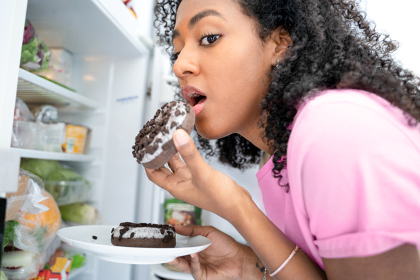 One black woman snacking tempted by sugar sweeties - Фото, изображение