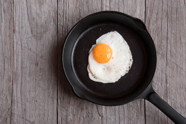 fried egg with bacon and tomato on a wooden background - Foto, Imagem