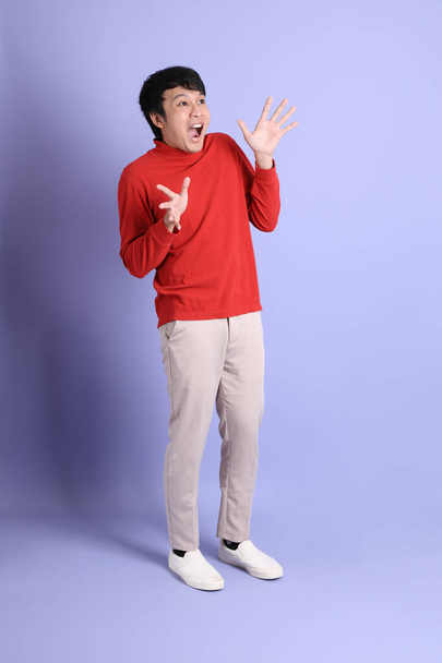 The young adult southeast Asian man with red long sleeve shirt standing on the light green background. - Photo, image