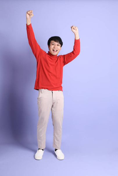 Mladý dospělý jihovýchodní Asiat muž s červeným dlouhým rukávem košile stojící na světle zeleném pozadí. - Fotografie, Obrázek