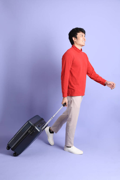 El joven adulto del sudeste asiático hombre con camisa roja de manga larga de pie sobre el fondo verde claro. - Foto, imagen