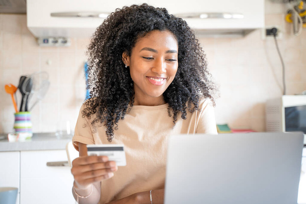 Одна счастливая черная женщина делает покупку кредитной карты из дома - Фото, изображение