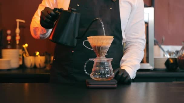 Preparación de café. El camarero vierte agua hirviendo sobre el café y lo filtra - Imágenes, Vídeo