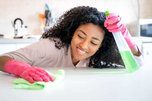Een zwarte vrouw schoonmaken huishoudelijke keuken thuis - Foto, afbeelding