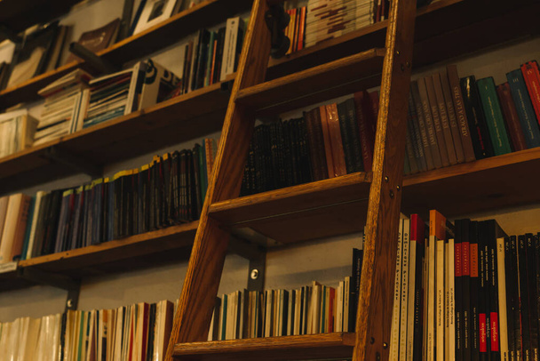 Zestaw książek ułożonych na wysokich półkach, z drewnianą drabiną w popularnej księgarni w Lizbonie, Portugalia. - Zdjęcie, obraz