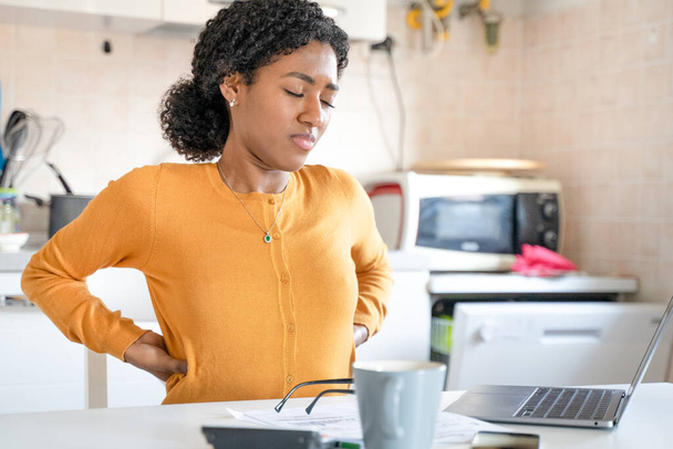 Moe zwarte vrouw werken vanuit huis lijden rugpijn - Foto, afbeelding