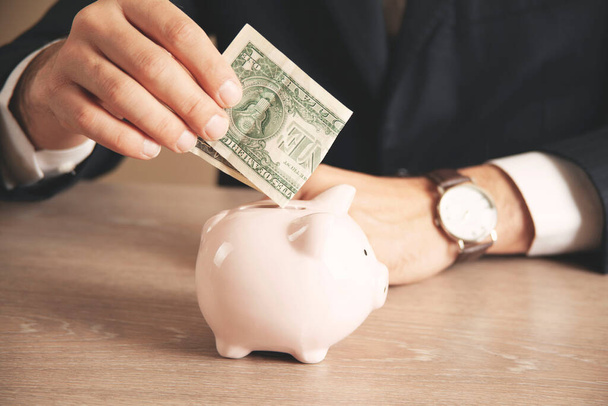 Man putting coin in piggy bank. saving money, finance concept - Zdjęcie, obraz