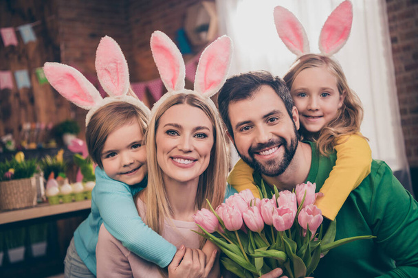 Photo of cute lovely family with bunny ears celebrate easter holiday father hold present for mother bunch of flowers - Foto, Imagen