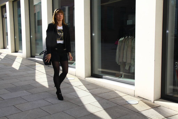 attractive, fashionably dressed lady is walking through a shopping street - Фото, зображення