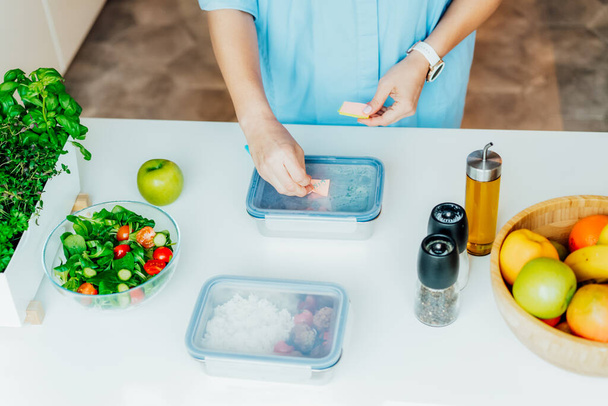 Healthy diet plan for weight loss, daily ready meal menu. Close up woman putting note on lunch box cooked in advance, ready to eat for dinner. Balanced portion with healthy dish. Pre-cooking concept. - 写真・画像