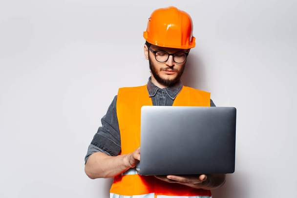 Portrait of young construction engineer using laptop on white background. - Photo, Image