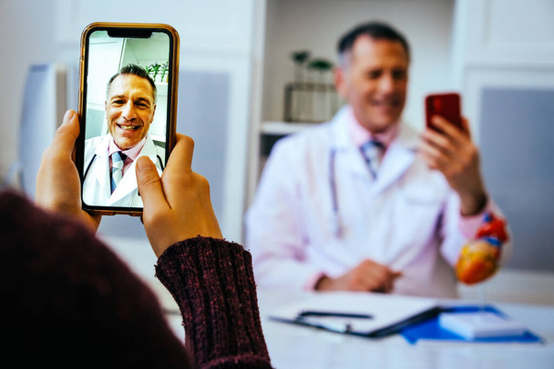 doctor y paciente discutiendo algo usando teléfonos inteligentes en el hospital - Foto, imagen
