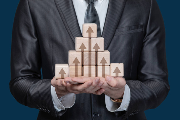 Business profit growth concept. Businessman showing a pyramid of cubes with growth arrows. - Photo, Image