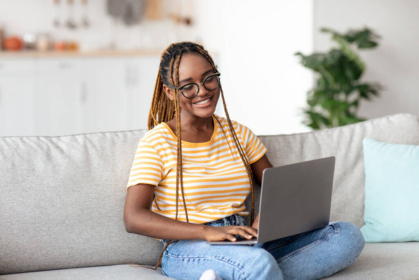 Happy black woman typing on laptop keyboard, home interior - Foto, imagen