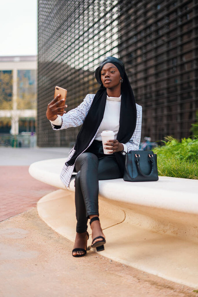 Θετική στιλάτη μουσουλμάνα μαύρη γυναίκα που παίρνει selfie στο smartphone - Φωτογραφία, εικόνα
