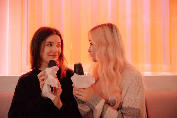 LGBT Lesbian couple eat sushi rolls in asian cafe with red light - Fotografie, Obrázek