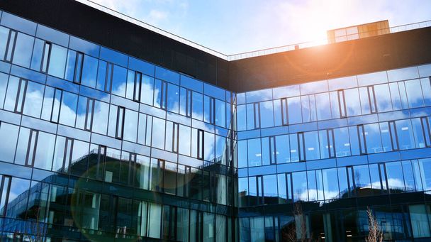 Modernes Bürogebäude mit Glasfassade vor klarem Himmel. Abstrakte Nahaufnahme der glasverkleideten Fassade eines modernen Gebäudes mit reflektierendem Plattenglas. - Foto, Bild