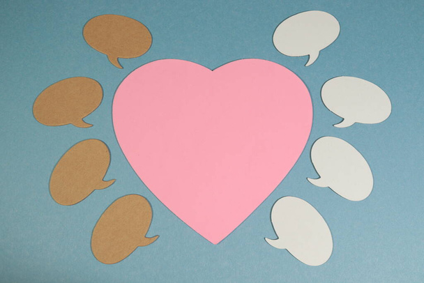 Πολλές φυσαλίδες ομιλίας γύρω από μια μεγάλη ροζ καρδιά σε ένα μπλε φόντο - Φωτογραφία, εικόνα