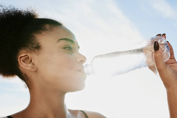 Robię sobie przerwę na H2O. Zbliżenie na sportową młodą kobietę pijącą wodę po treningu. - Zdjęcie, obraz