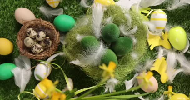 Huevos de Pascua coloridos en la hierba. Vista superior giratoria de huevos de Pascua de colores acostados sobre fondo verde de Pascua. - Metraje, vídeo