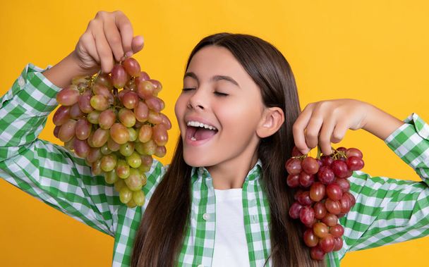 happy teen girl with grapes bunch on yellow background - Fotoğraf, Görsel