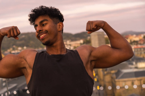 Arab young bodybuilder doing sports in the city, showing off his big arm muscle - Fotó, kép