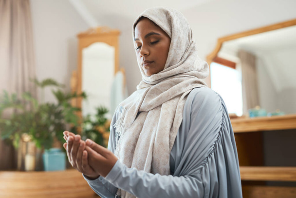 Prayer should not be regarded as a duty. Shot of a young muslim woman praying in the lounge at home. - Foto, Imagem
