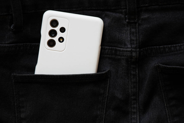 Ukraine Dnipro 05.04.2022 - новий смартфон Samsung A52 у білій коробці лежить у кишені сірих штанів, купує нові гаджети. - Фото, зображення