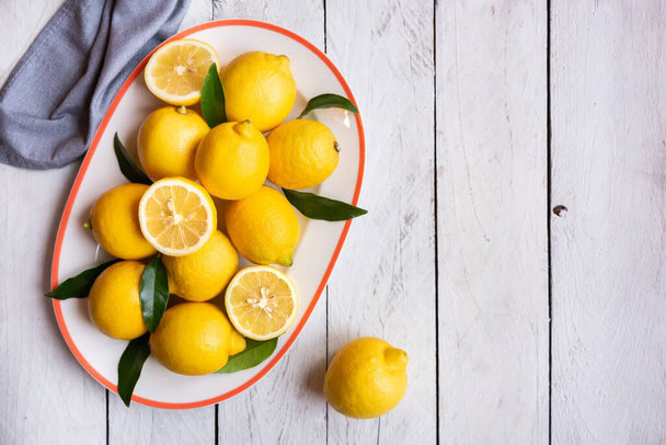Čerstvé a zralé citrony s listy na bílém dřevě - Fotografie, Obrázek