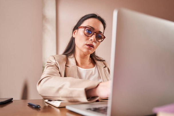 Terapeuta feminina olhando para a tela do laptop e sentindo-se sério enquanto trabalhava - Foto, Imagem
