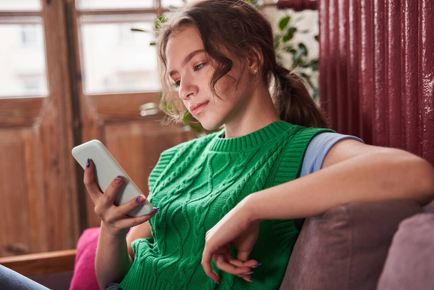 Ergenlik öncesi genç kız otururken akıllı telefonuyla mesaj atıyor. - Fotoğraf, Görsel